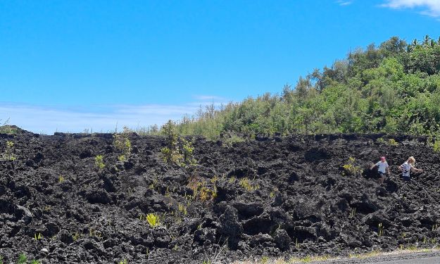 Kids walking on a black lava field from a past eruption on Big Island Hawaii.