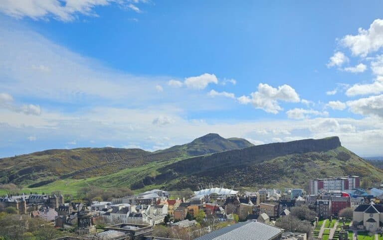 A city view with a grass volcanic hill. Known as Arthurs Seat is a popular walk in Edinburgh,