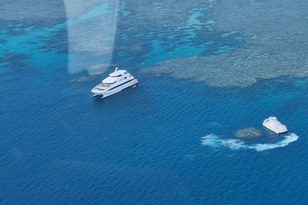 A helicopter view of the Barrier Reef and blue ocean with two white boats.