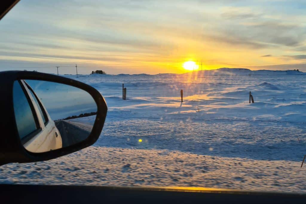 Snowy landscape at sunrise from a car during a road trip to Iceland.