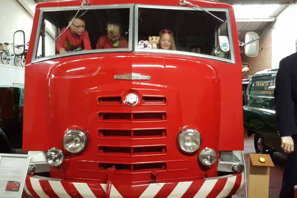 Kids playing on a vintage red vehicle at the Dundee Transport Museum.