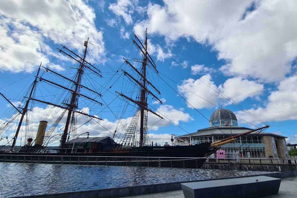 Old docked sailing ship with buildings in Dundee.