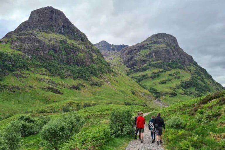 A family hiking with kids on a path towards rocky hills.