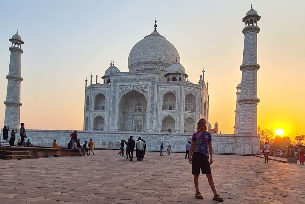 Kid stood in front of an iconic white building in India at sunrise. 