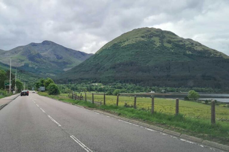 A road heading towards green rolling hills in Scotland