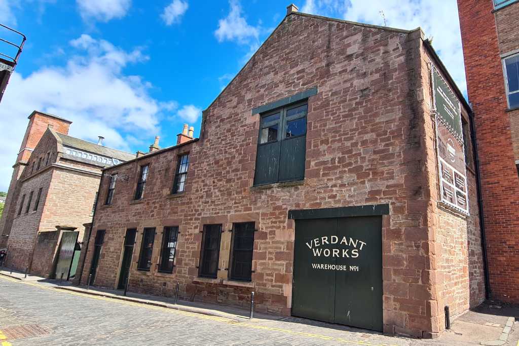 Brick building with windows and door stating Verdant Works  Warehouse #1 