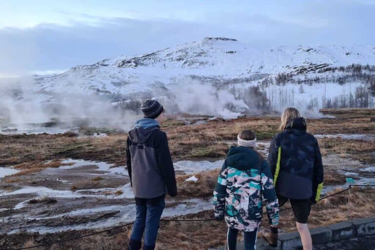 Kids watching geothermal activity in a field in Iceland.