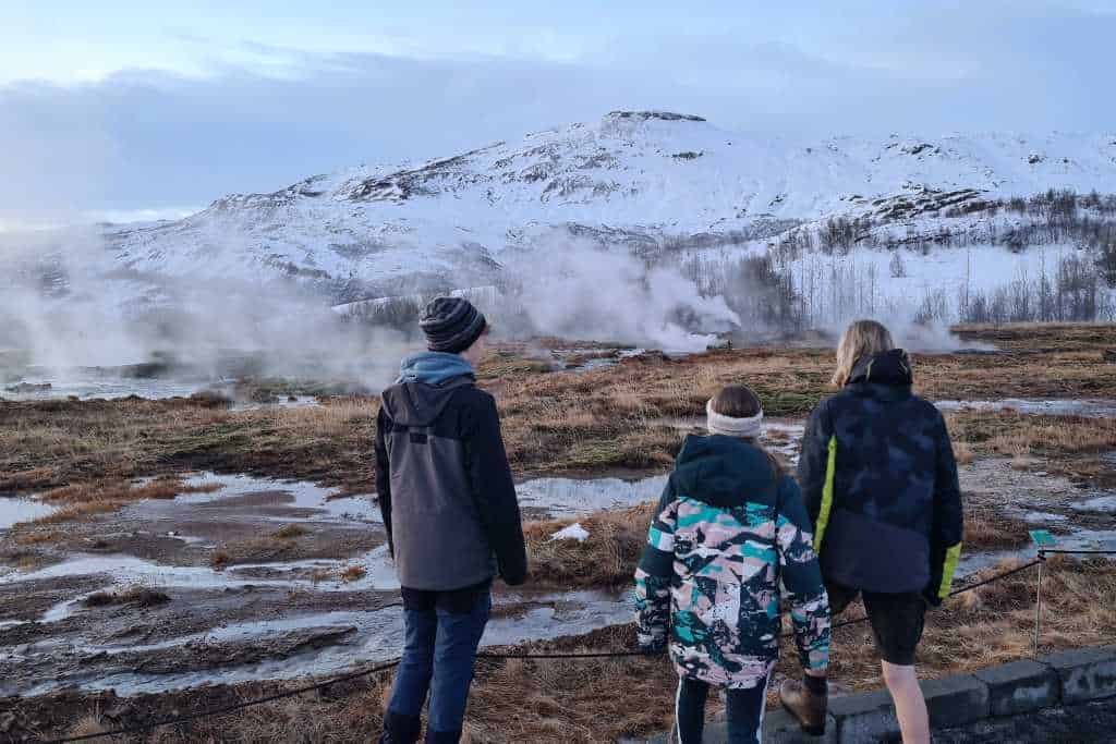 Kids watching geothermal activity in a field on a visit to Iceland.