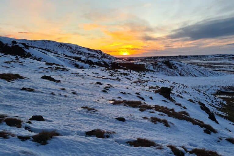 A snowy field at sunrise in Iceland. Hiking is a free activity to help your budget in Iceland.