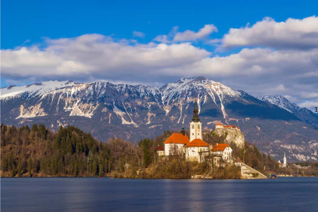 European fairy tail castle on a lake surrounded by snow capped mountains in winter.