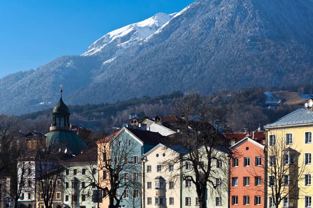 Colourful houses and snow covered mountains in a European city in winter.