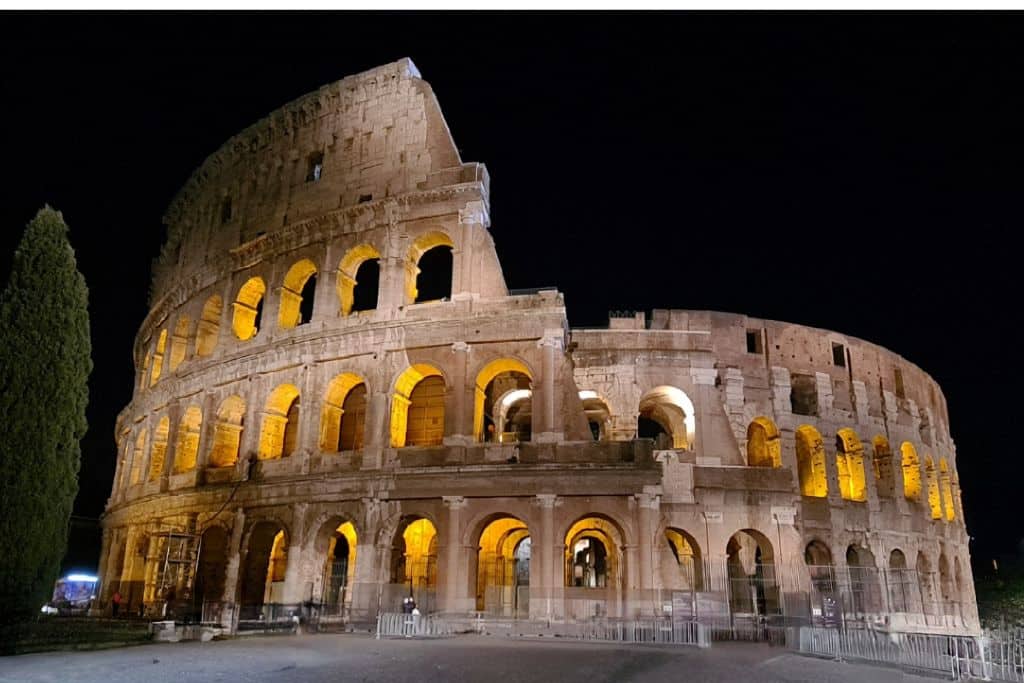 A lit up ancient round building at night in Rome.