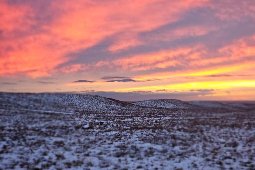 Sunset over a field that has some snow in Iceland.