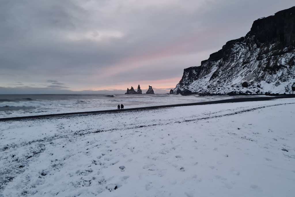 A snowy beach with pinnacles in the sea.