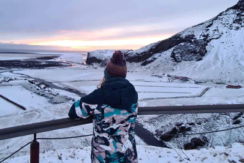 A kid looking away over a snowy outlook in winter.