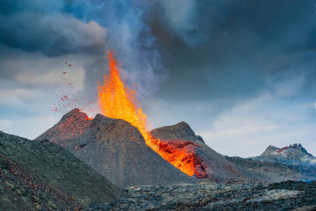 Erupting volcano with orange lava spouting in Iceland.