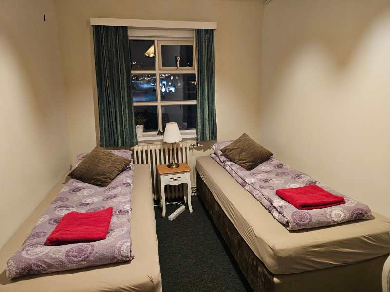 Two single beds in a small room with a window set ready for guests.