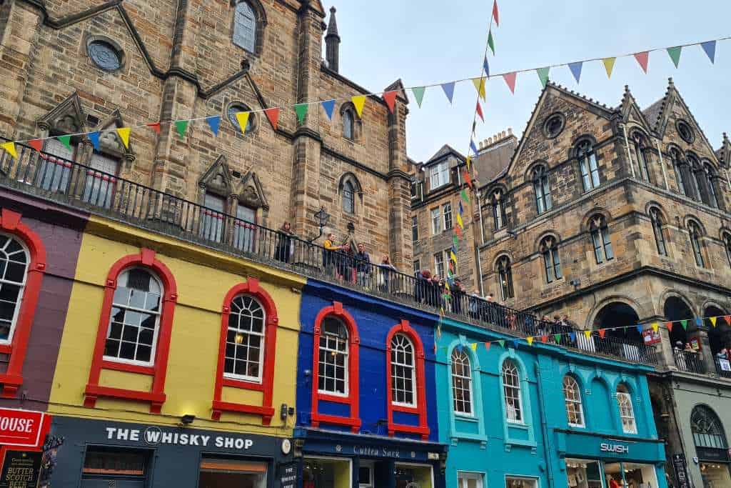 An old street with historic and colourful character. Colourful shops and flags in a popular Edinburgh street.