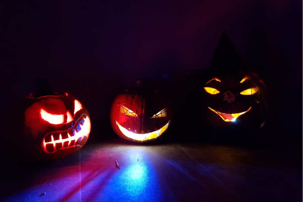 Three carved pumpkins illuminated in the dark.