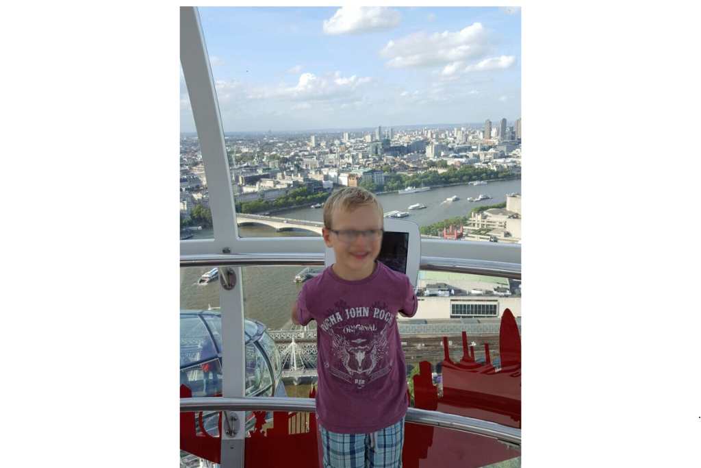 A kid in a glass capsule on the London eye with a city view.