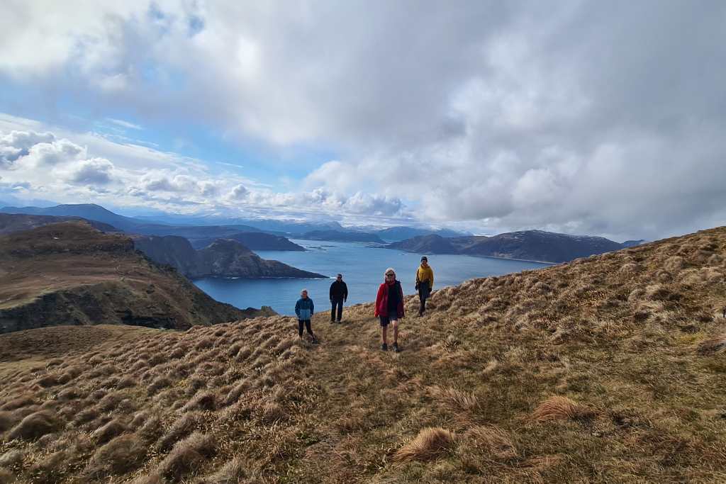 A family stood on a grassy hill overlooking sea in Norway on a bucket list trip.