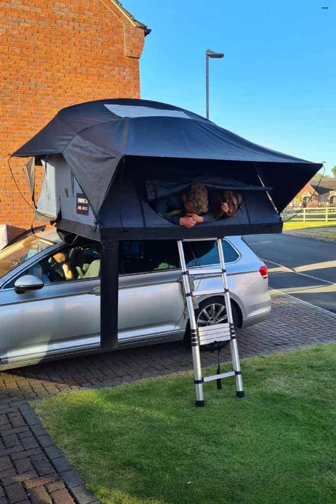 Rooftop tent on a car with children inside.