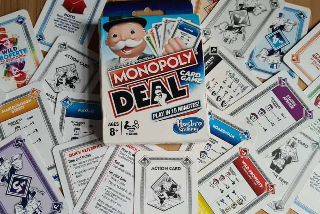 A pack of cards scattered out of the box. Monopoly Deal is a popular family card game that is great for travel families.