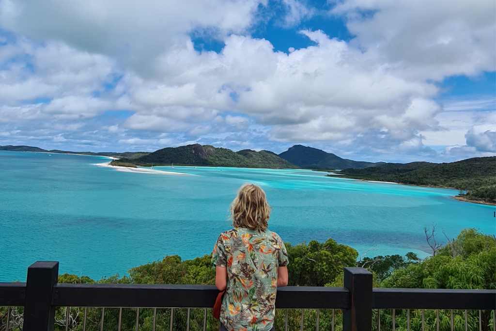 A teen looking out over blue sea and green islands. The Whitsundays is a bucket list destination for families visiting Australia.