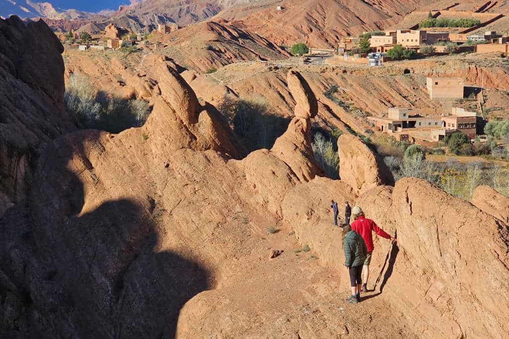 Kids climbing red rock formations in a desert in Morocco.