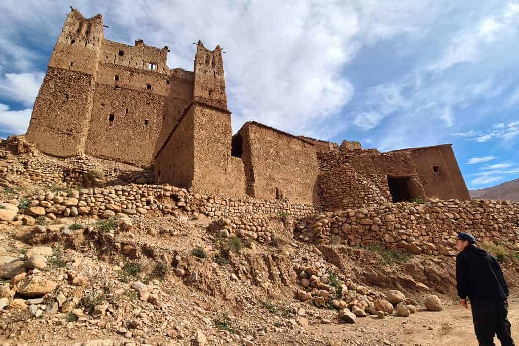 A kid looking at a mud built building on rocky ground in Dades  Valley Morocco.