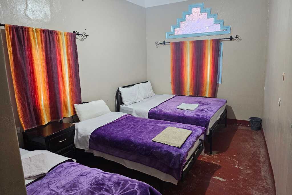 A triple bedroom with 2 windows in a budget hotel in Morocco.