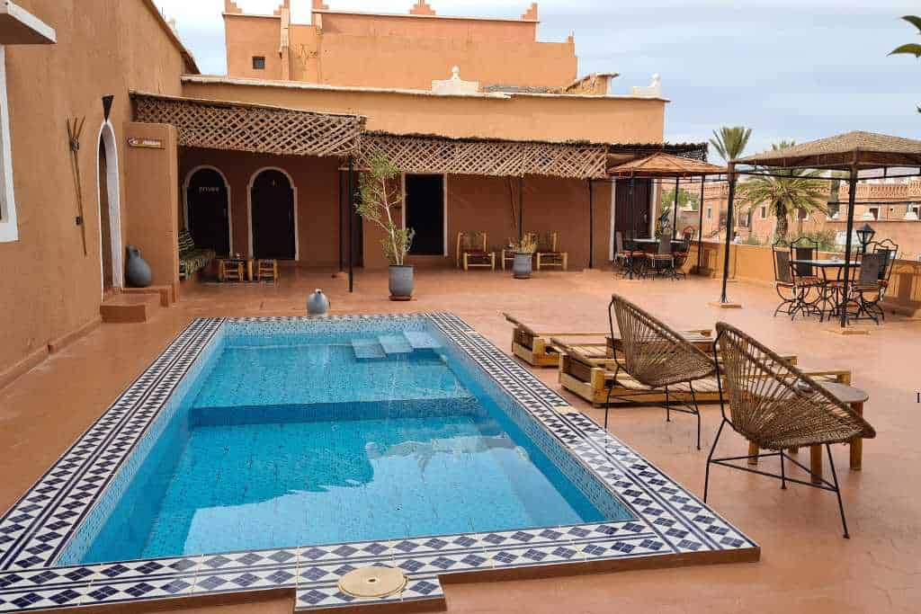 A pool on a tiled terrace in a riad in Morocco offering a view over Ait Ben Haddou. 