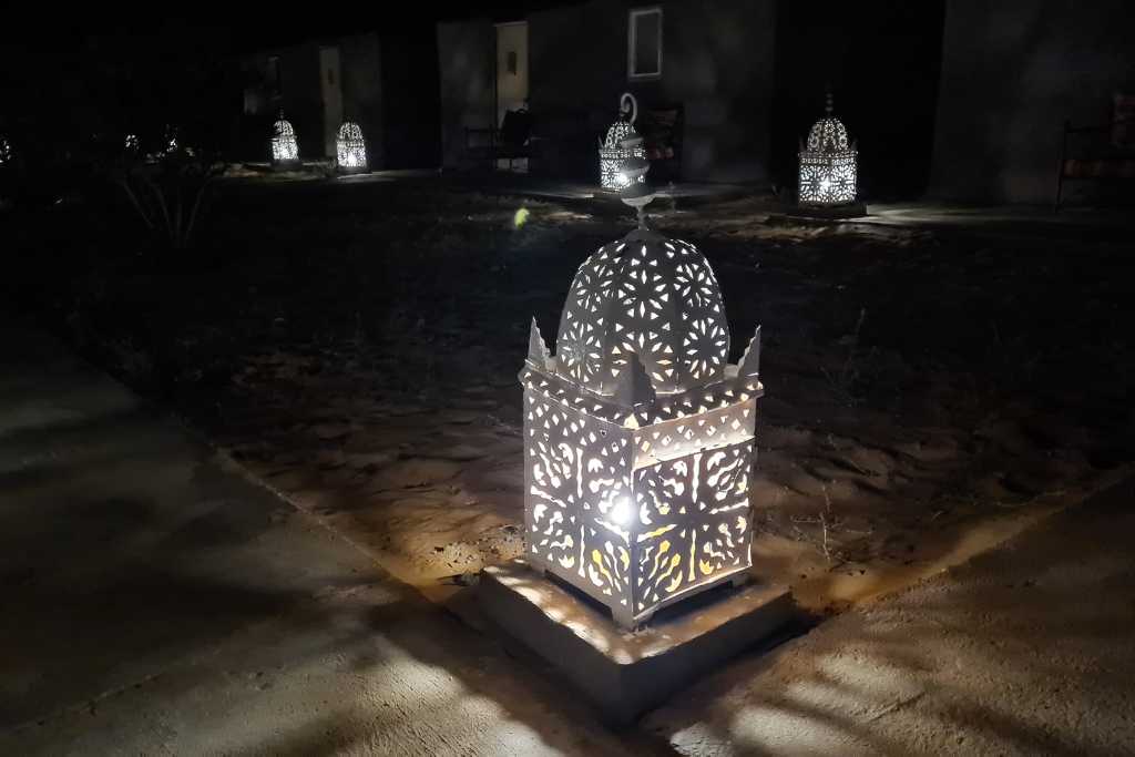 Moroccan lanterns lighting up the paths at night in a Sahara desert camp.