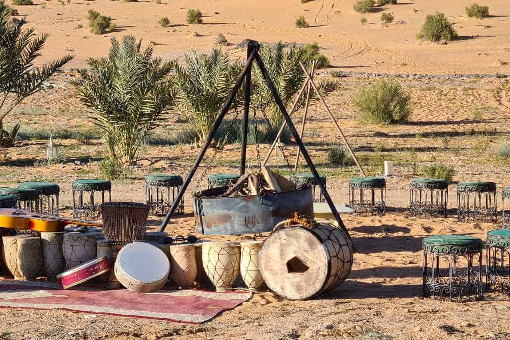 A fire pit, drums and chairs set out in the desert. Attending a Berber campfire in the Sahara Desert is a great options for families.