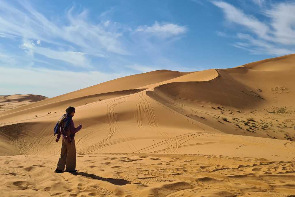 A child stood on golden sand dunes in Erg Chebbi desert, Morocco.