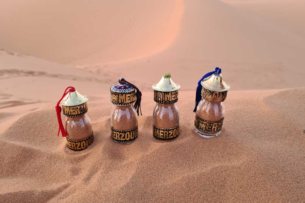 Four bottles in the sand on a dune in the Sahara Desert.