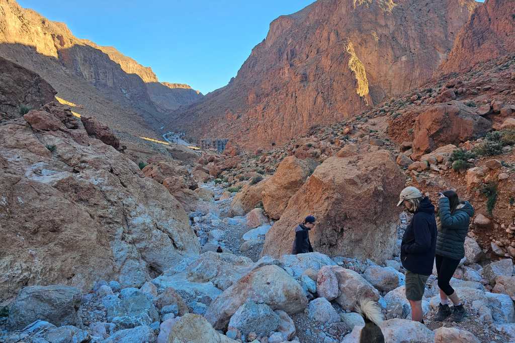 Kids hiking down large rocks in a valley in Dades Gorge Morocco.