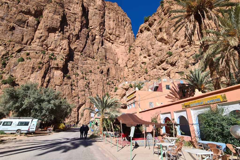 A hotel at the entrance to a gorge with palm trees. Todra Gorge is a popular place to add to a Moroccan itinerary.