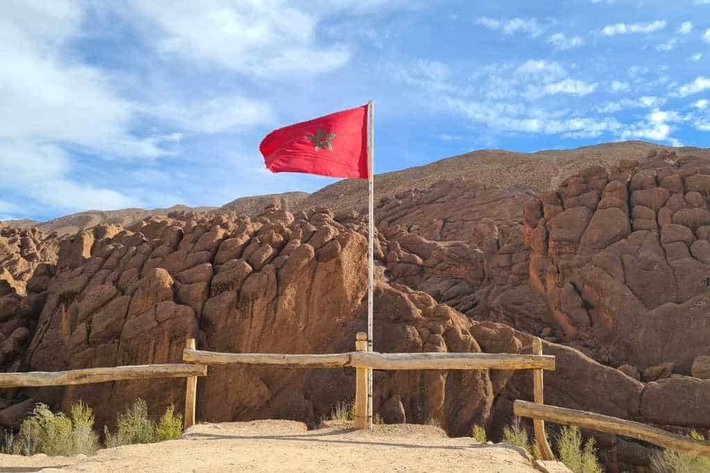 Red flag with green star flying at a viewpoint of a rocky mountain. A popular stop on a Morocco road trip.