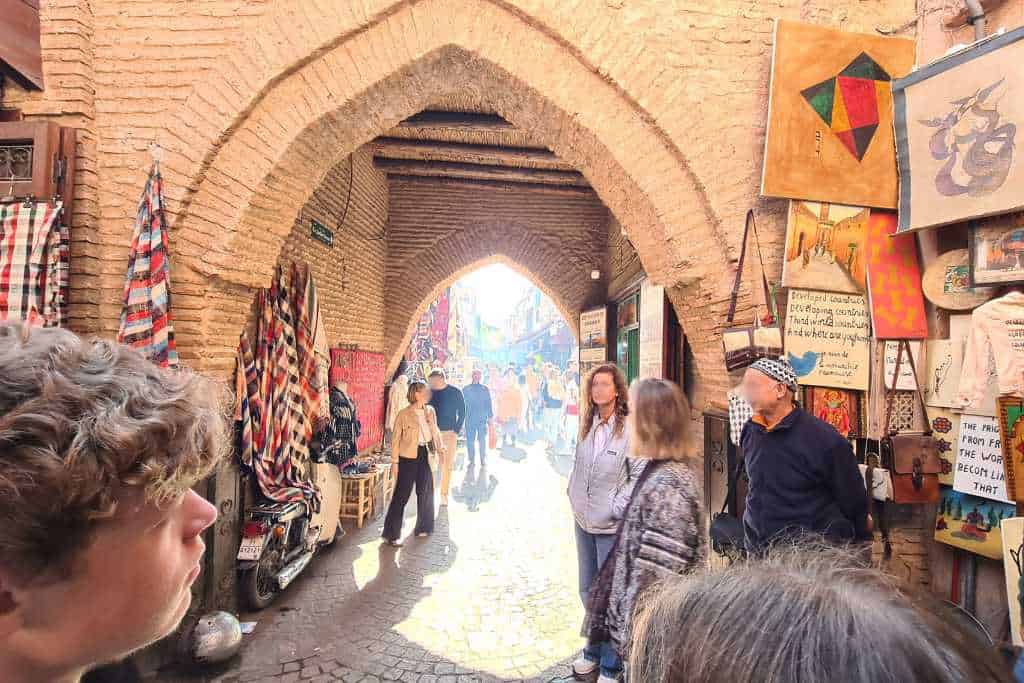 An archway with people in a market selling rugs in Morocco.