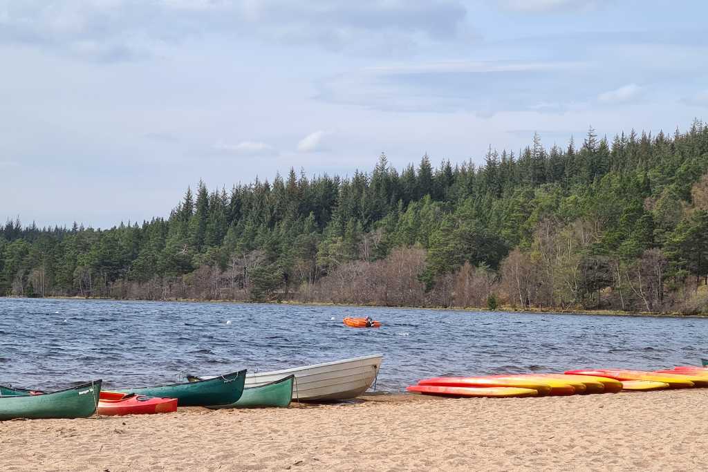 Kayaks on a beach next to water and forest in the Cairngorm National Park. A place to visit for a family day out in Scotland.