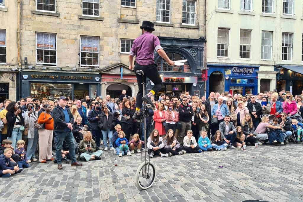 Crowds watching a street performer on a uni-cycle during the Edinburgh Fringe Festival.