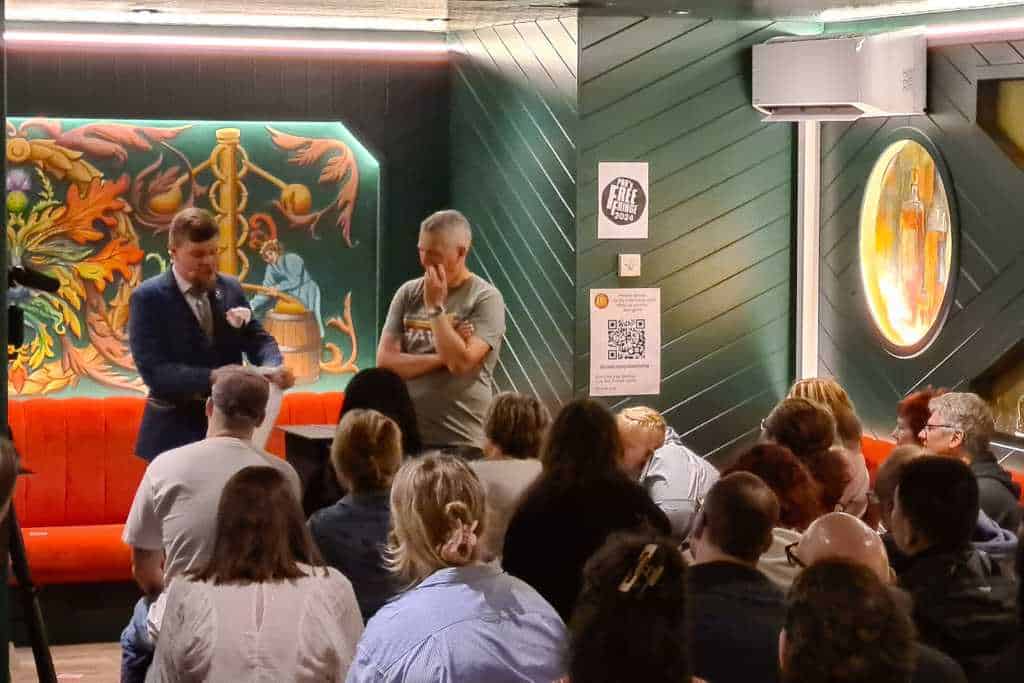 Two men doing a magic show in a crowded room in Edinburgh enjoying a festival.