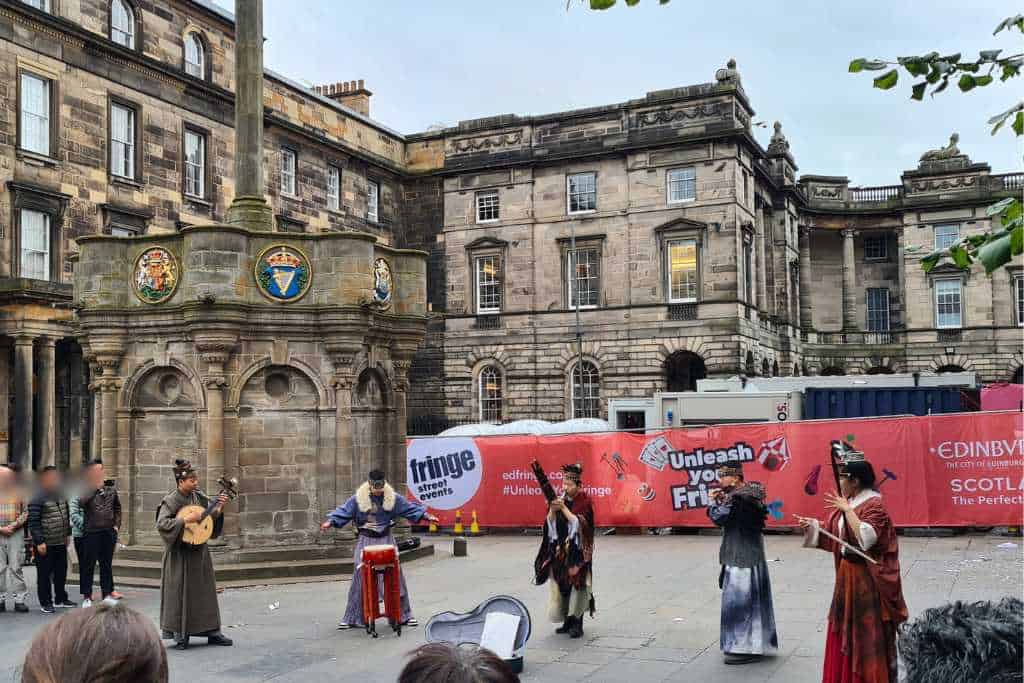 Street performers entertaining a crowd of spectators during the Edinburgh Fringe.