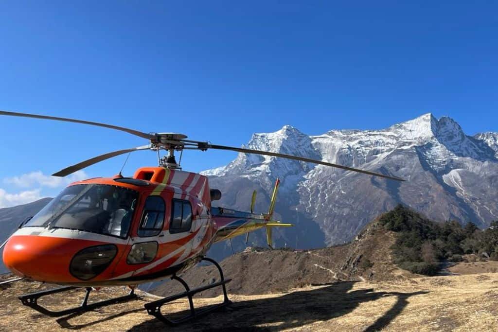 Helicopter waiting to fly with snowy mountains in the background.