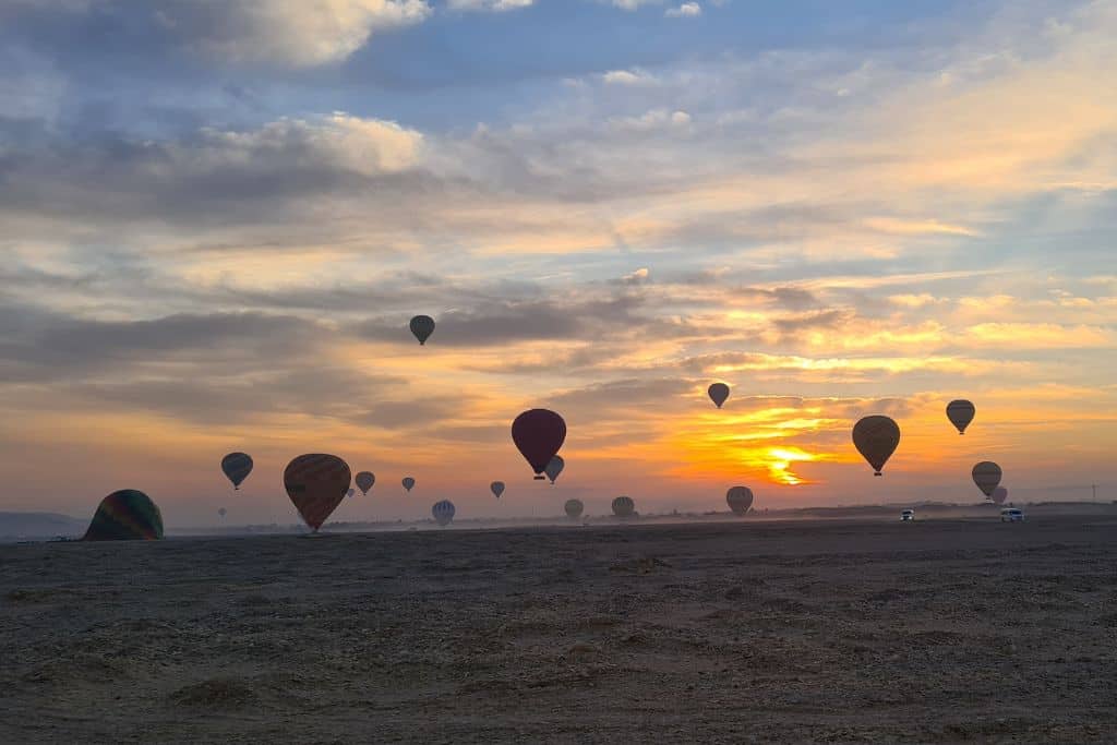 Multiple hot air balloons landing after a bucket list sunrise flight in Luxor, Egypt.