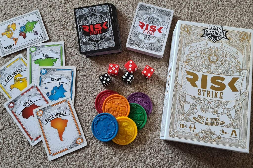 The strategic Risk card game laid out with colourful cards, coins and dice ideal size for travelling families.