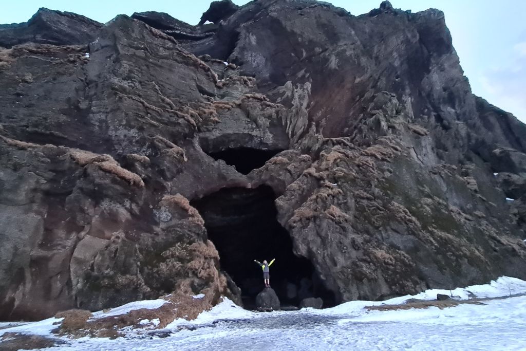 A popular cave in a large rock formation surrounded by snow in Iceland.